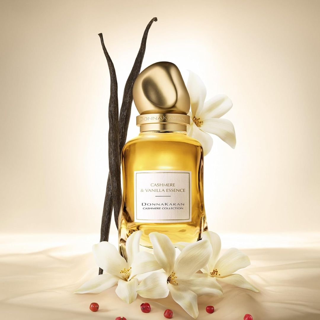 Perfume bottle with vanilla beans and flowers on a beige background